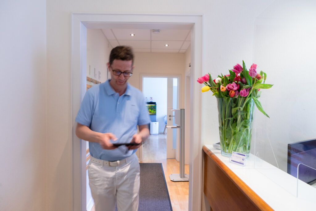 Zahnarzt Herr Meyer-Stolten läuft durch seine Praxis, immer mit einem freundlichen Lächeln und einem Blick für das Wohl seiner Patienten, um sicherzustellen, dass alles reibungslos läuft.